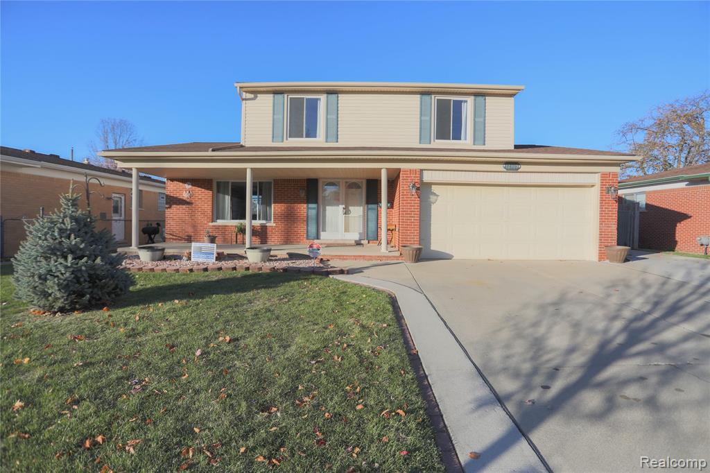 Photo for 12103 Diegel Road, Warren, MI 48093 - listing #20251054035 Traditional-style home with a porch, concrete driveway, brick siding, and a front yard