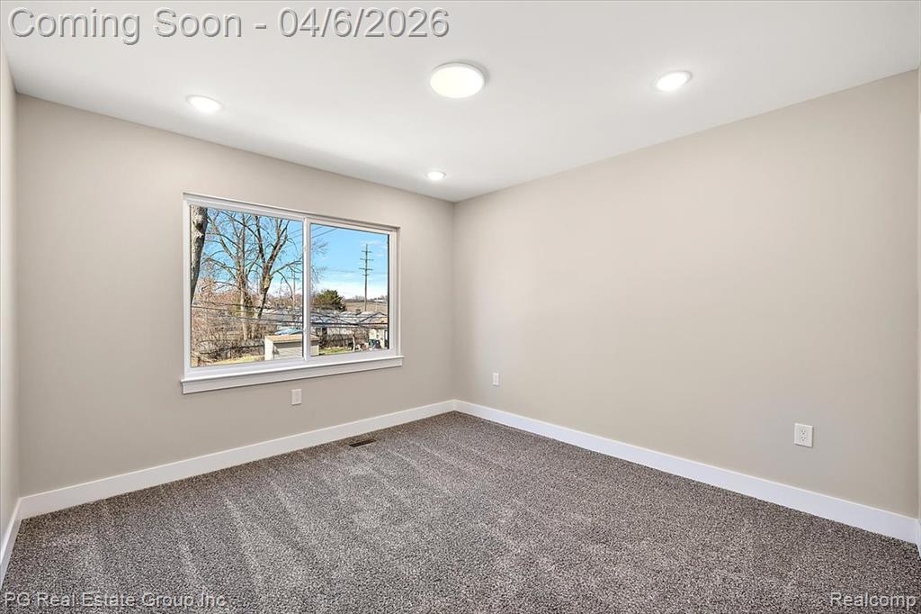 Empty room with dark carpet and recessed lighting