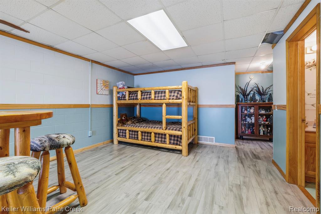 Wood-finish flooring, drop ceiling with recessed lighting, two-tone painted block walls, and natural wood trim accents