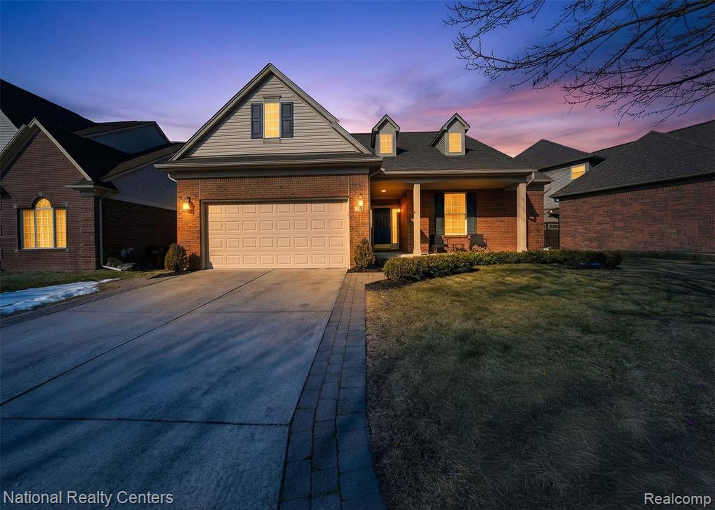 Traditional-style home with concrete driveway, brick siding, a lawn, and a porch