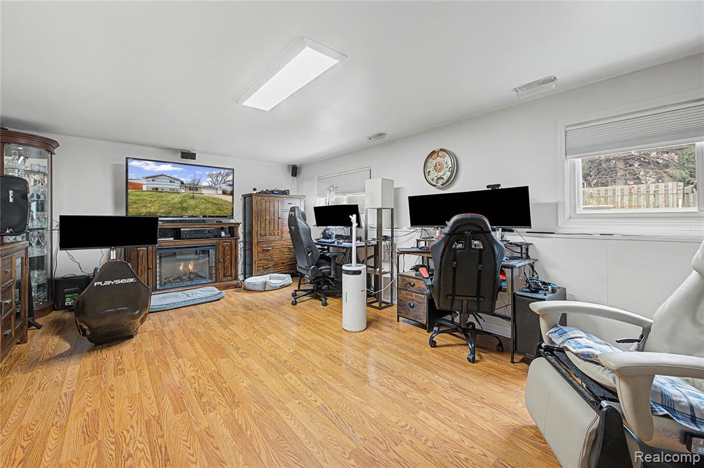 Home office with light wood finished floors and a glass covered fireplace