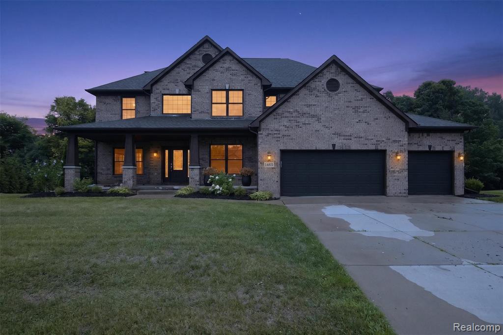 Brick exterior with multiple gables, covered front porch with stone-base columns, multi-pane windows, attached two-car garage, and an additional attached single-car garage