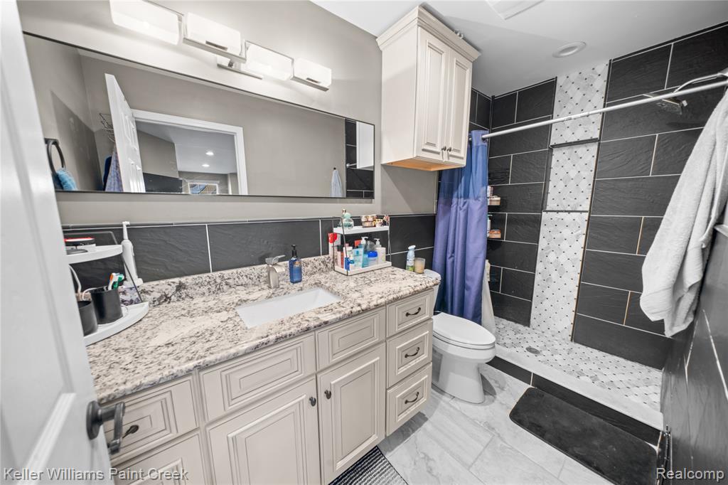Full bath with vanity, a stall shower, and tile walls
