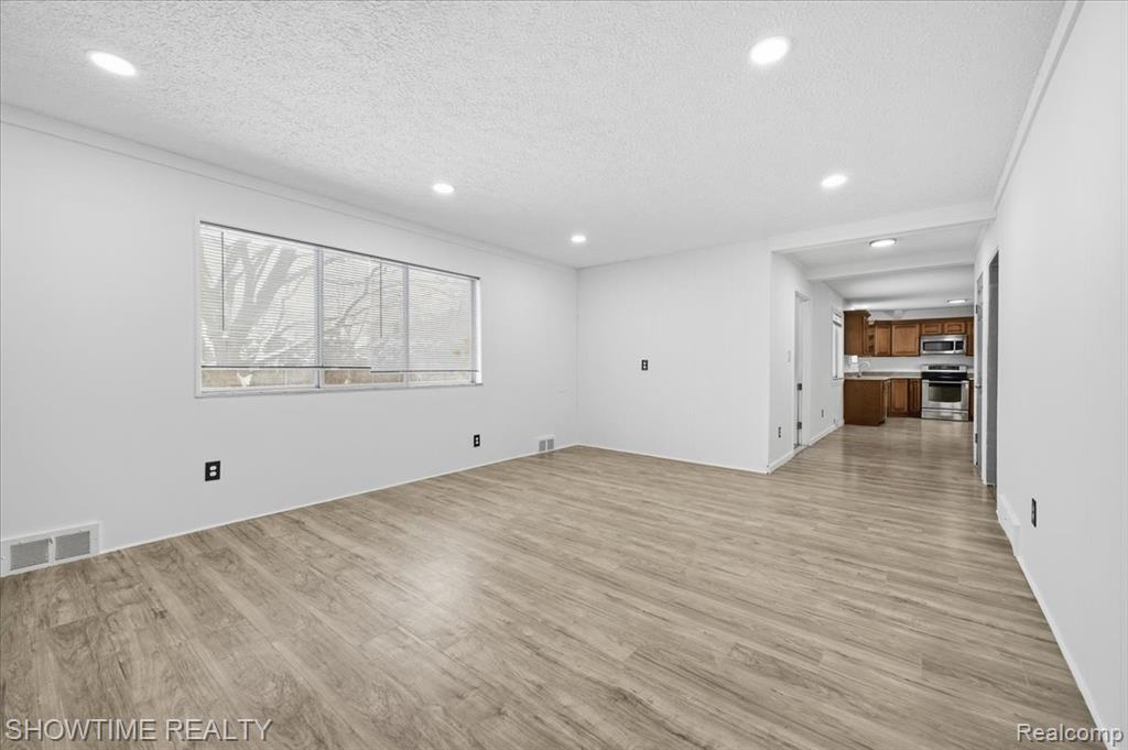 Unfurnished living room with light wood-style flooring, a textured ceiling, and recessed lighting