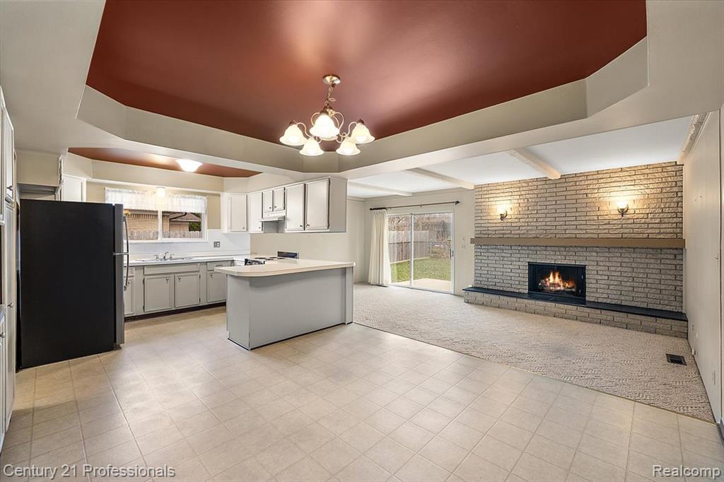Kitchen with freestanding refrigerator, light colored carpet, a peninsula, light countertops, and open floor plan