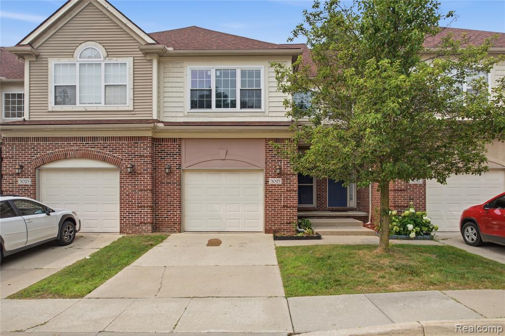 Multi-level townhouse exterior featuring brick and siding facade, individual garage access, and a prominent front entrance with steps