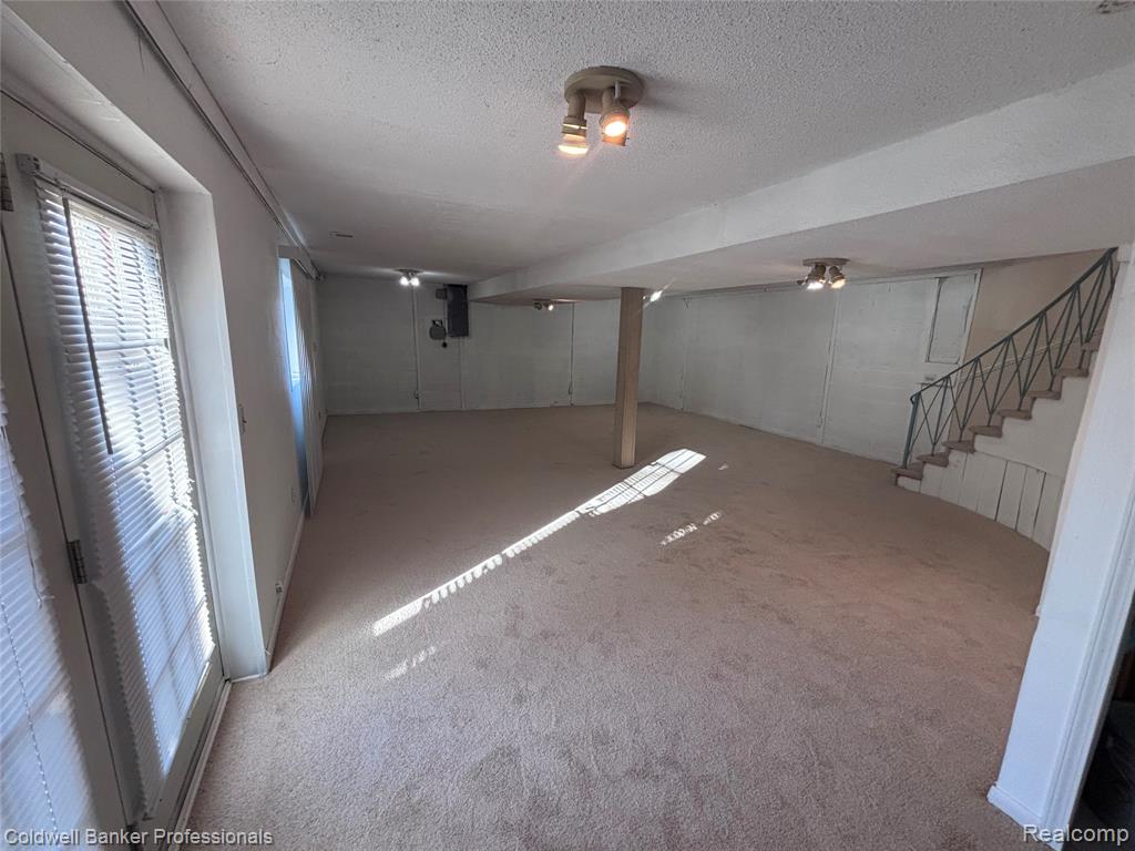 Basement with a textured ceiling, carpet, and stairway