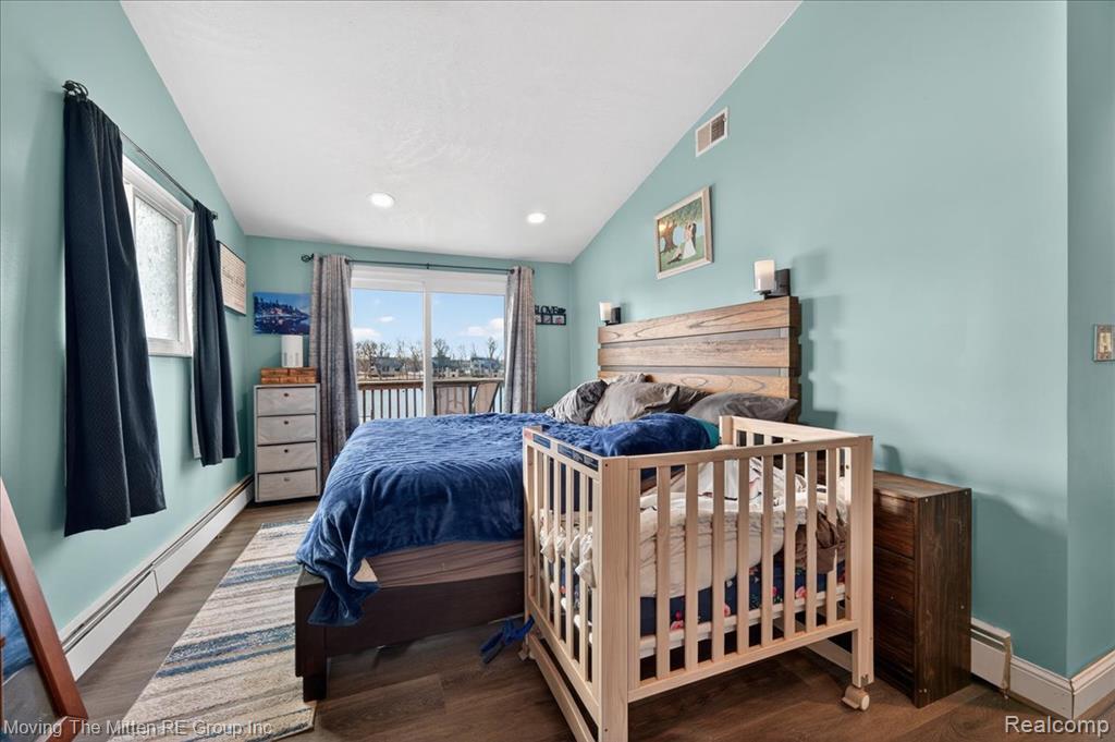 Bedroom featuring lofted ceiling, a baseboard radiator, dark wood-style floors, recessed lighting, and access to outside