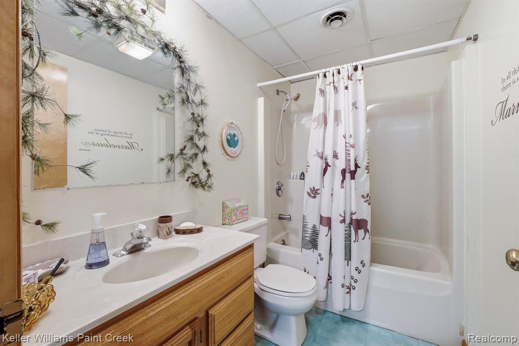 Bathroom featuring a single vanity with wood-finish cabinetry, a white countertop, and a built-in sink