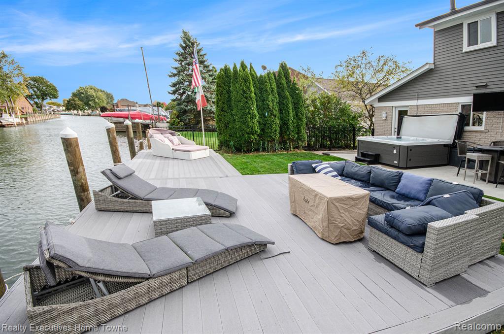 Wooden deck with a hot tub, a water view, outdoor seating, and a dock