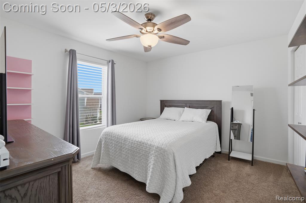 Carpeted bedroom featuring a ceiling fan