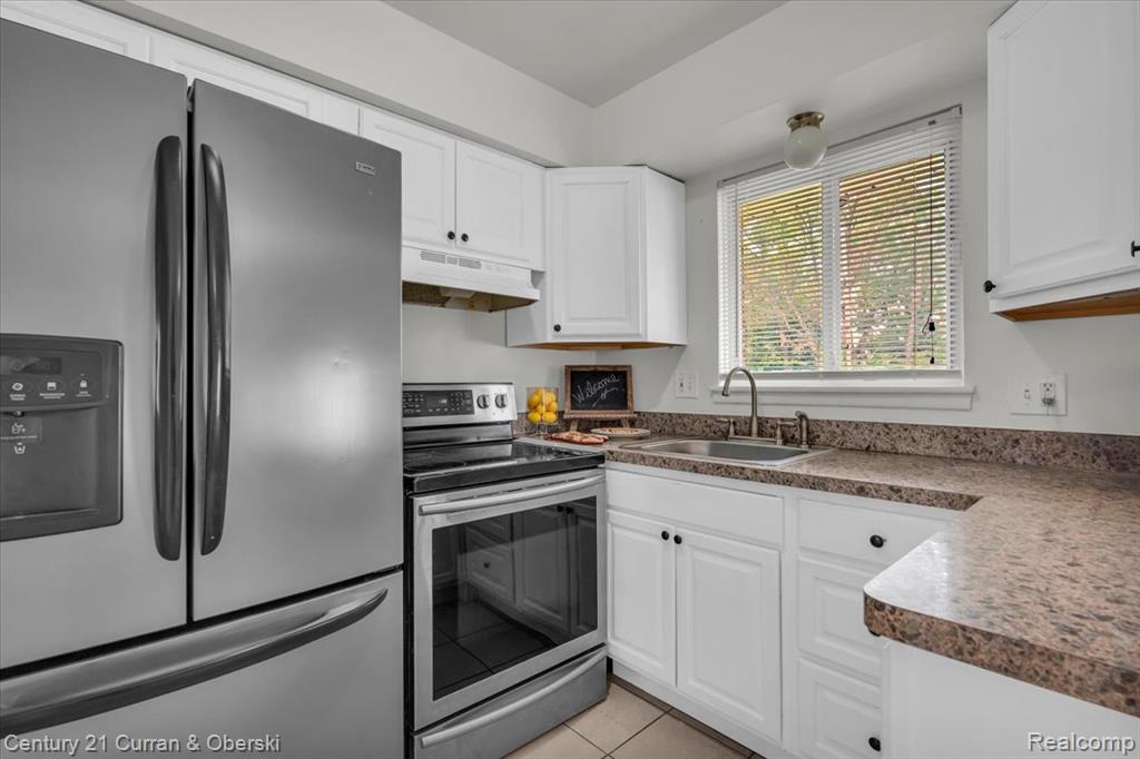 Kitchen featuring stainless steel appliances, white cabinets, and light tile patterned floors