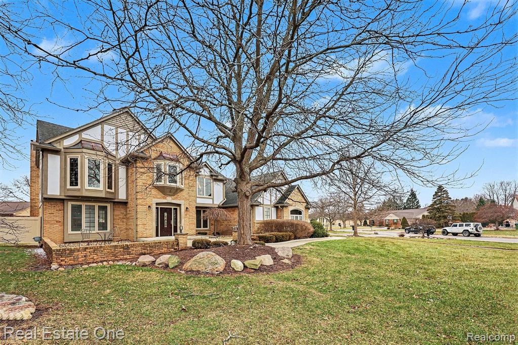 View of front of home with brick siding and a front lawn