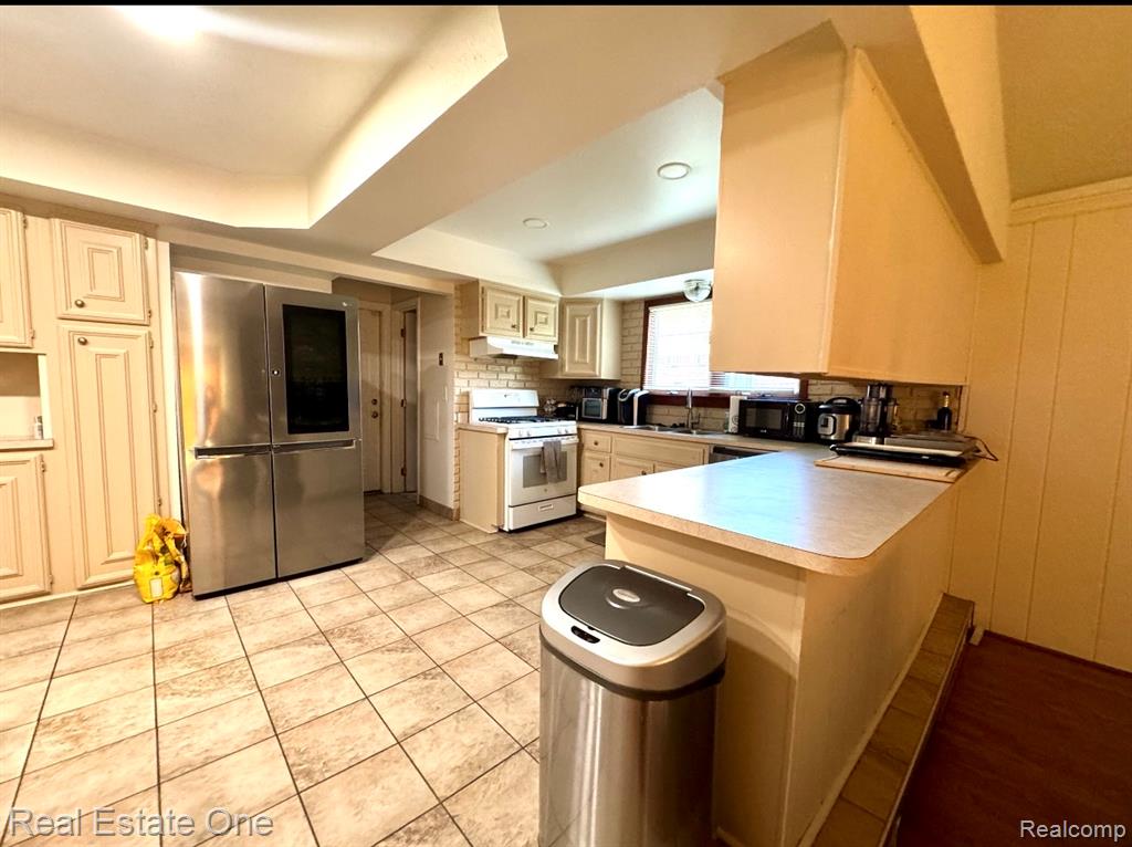 Unfurnished living room featuring a textured ceiling, a brick fireplace, wood finished floors, ceiling fan, and wooden walls