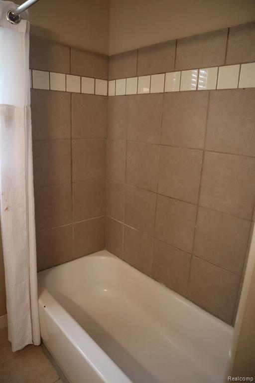 Full bath with shower / tub combo with curtain and tile patterned flooring