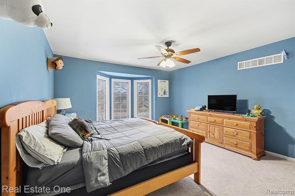 Carpeted bedroom with ceiling fan and baseboards