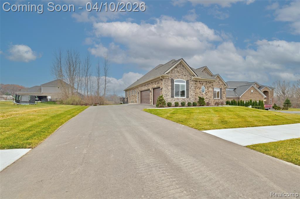 View of front of property with a front yard, a garage, asphalt driveway, and brick siding