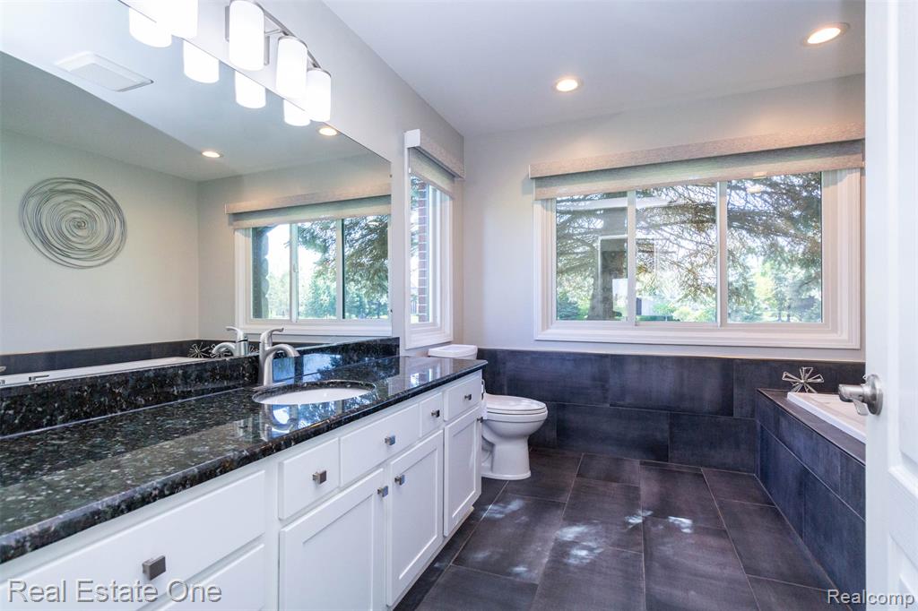 Full bathroom featuring granite counter sink/vanity, a whirlpool tub and porcelain tile floors