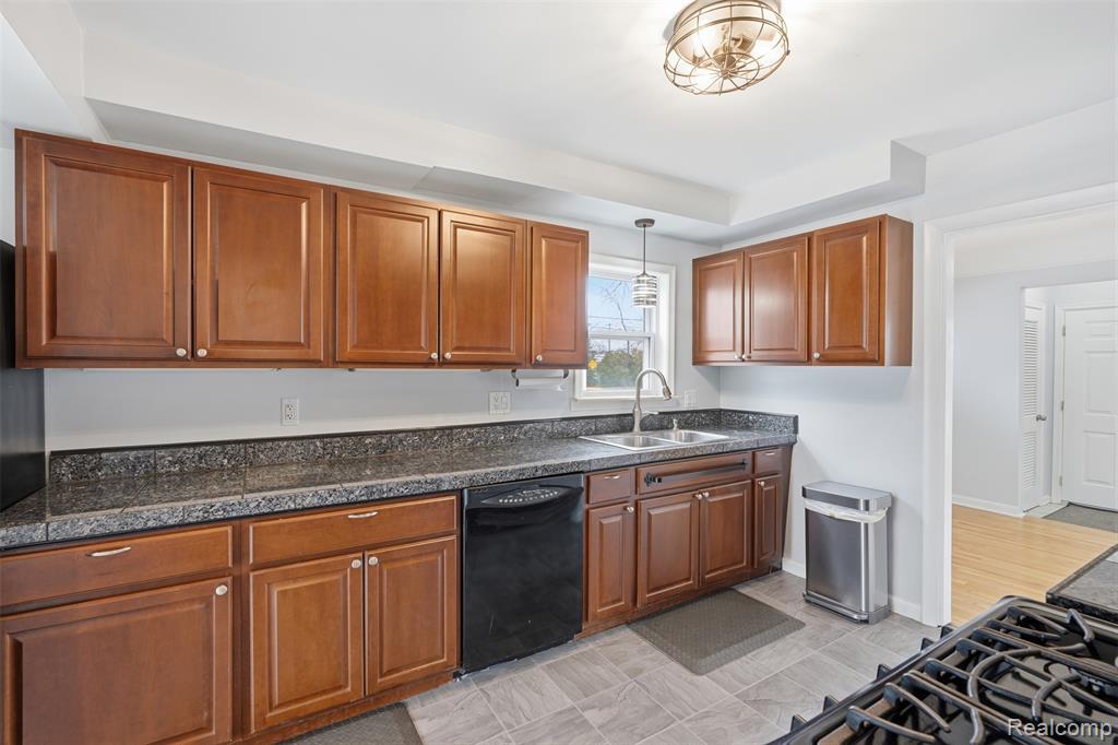 Kitchen featuring dark countertops, wood finish cabinetry, black appliances, and pendant lighting