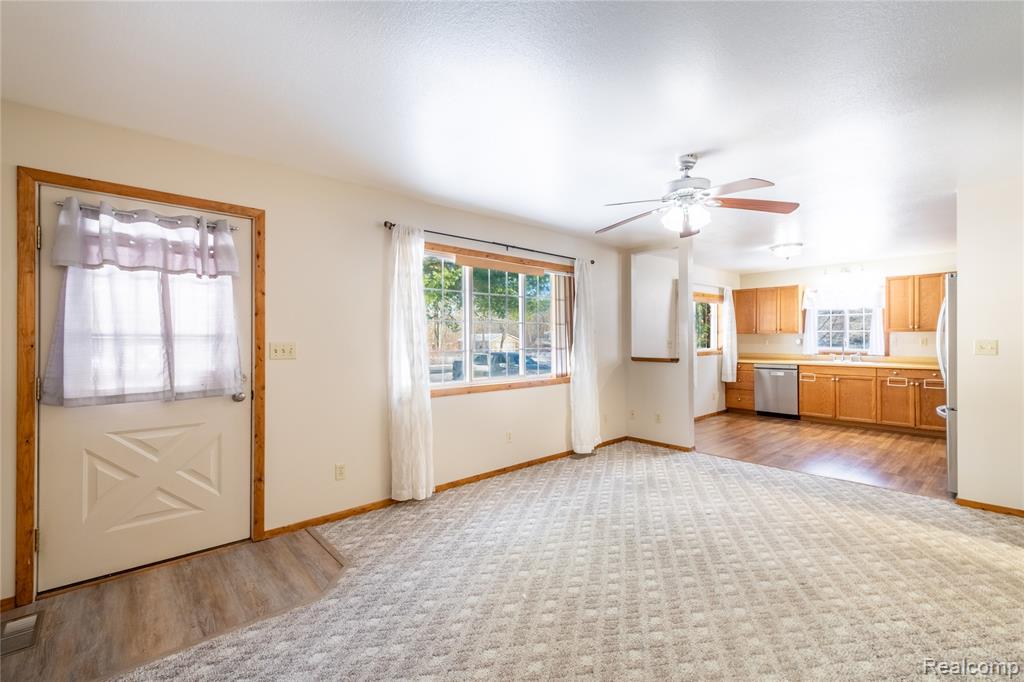 Unfurnished living room with a ceiling fan, light wood finished floors, and light colored carpet