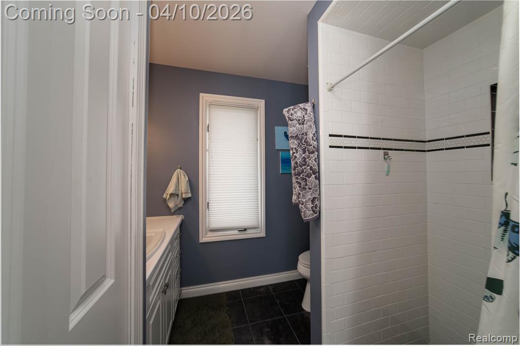 Bathroom with vanity, a shower stall, and dark tile patterned flooring