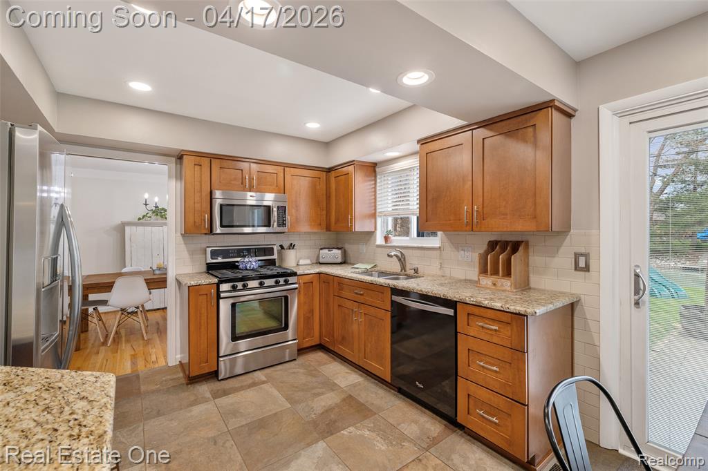 Kitchen with light stone countertops, stainless steel appliances, wood finish cabinets, recessed lighting, and backsplash
