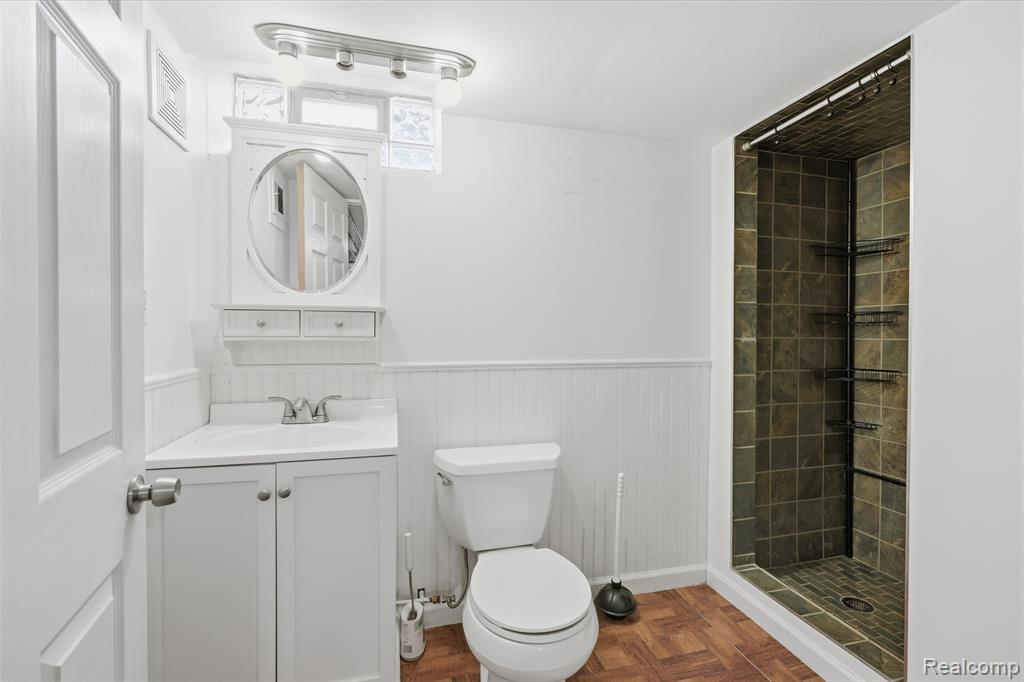 Bathroom with a shower stall, a wainscoted wall, vanity, and parquet flooring