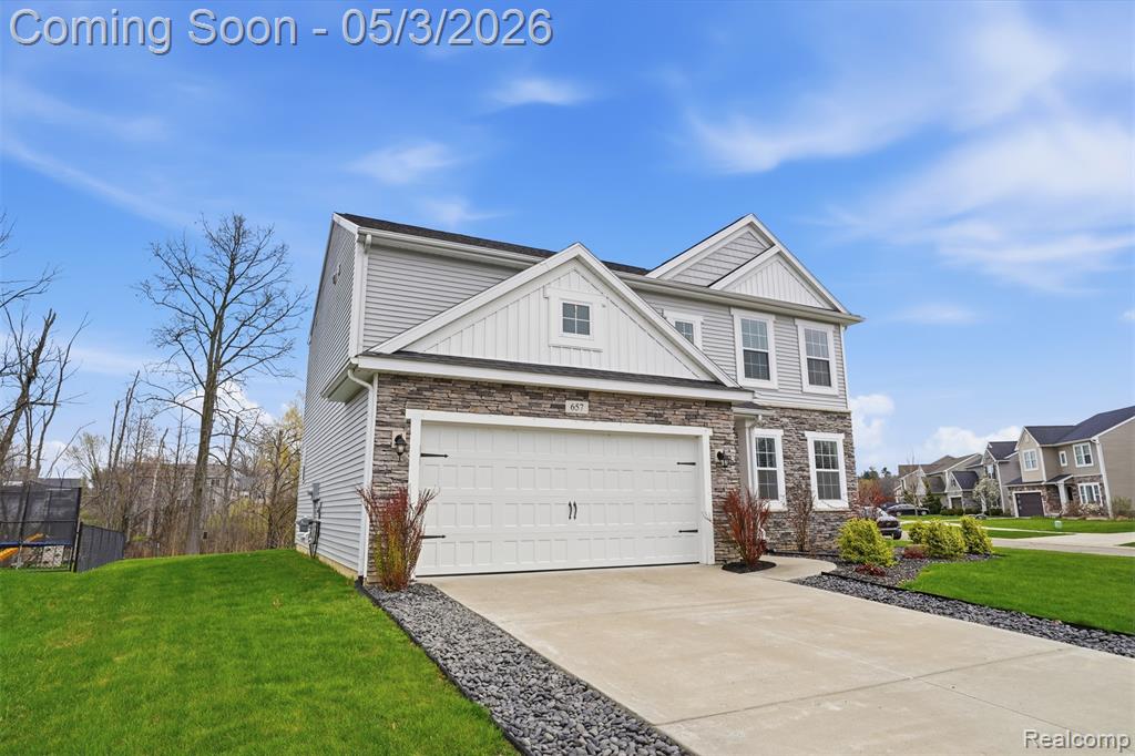Craftsman house featuring a front lawn, stone siding, driveway, and a garage