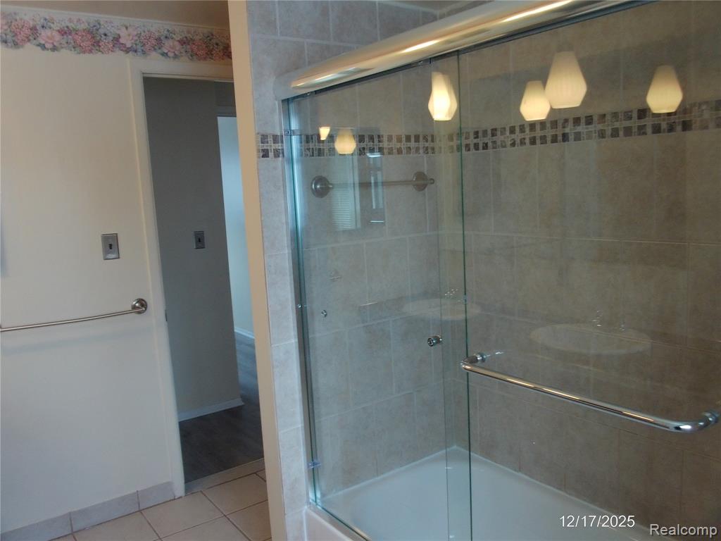 Full bathroom featuring combined bath / shower with glass door and tile patterned floors