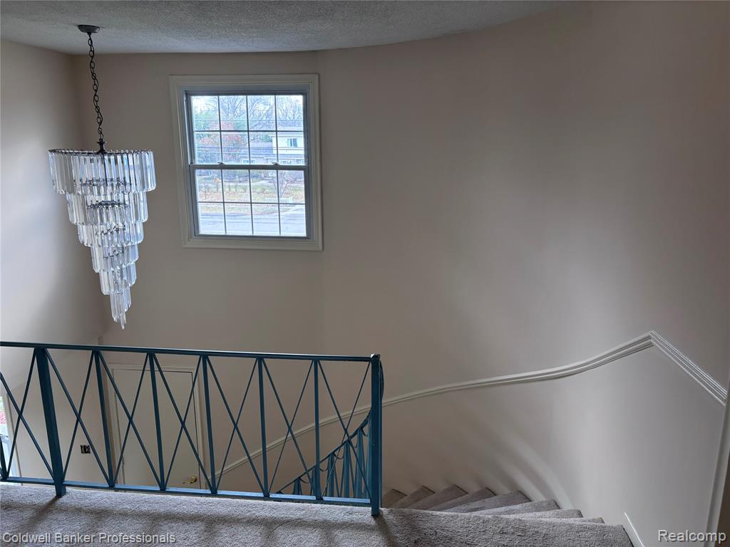 Stairway with a textured ceiling and carpet flooring and Chandelier