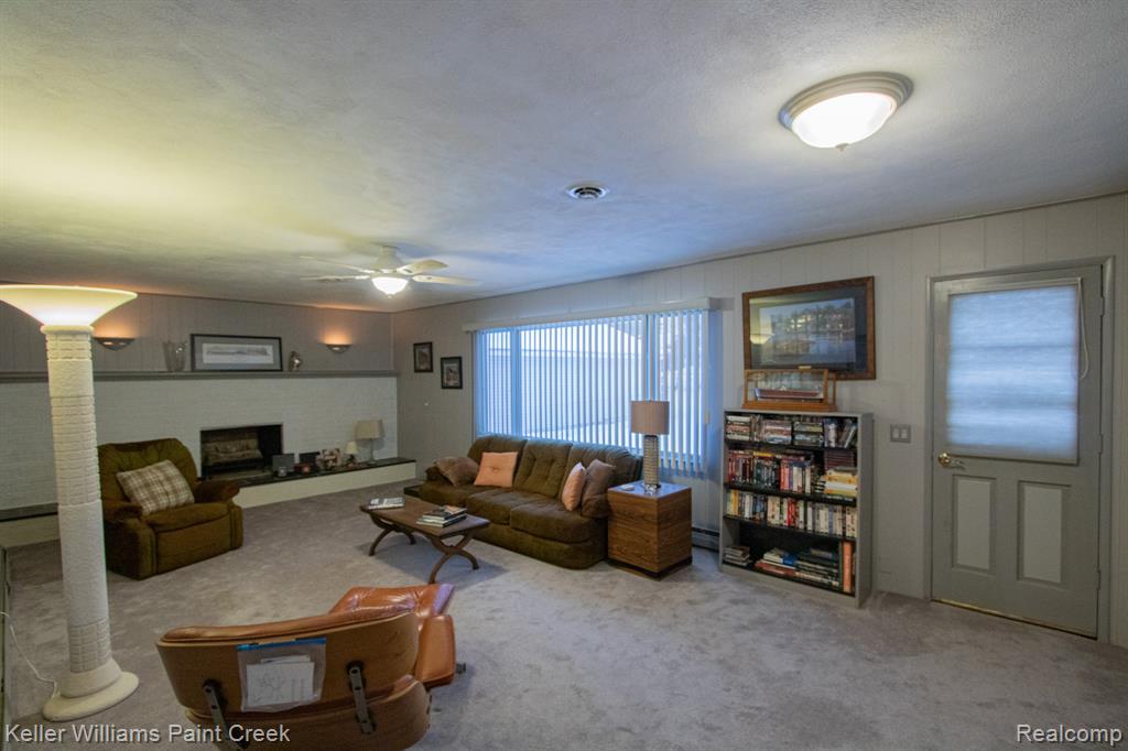 Carpeted living area featuring ceiling fan, a fireplace, and a textured ceiling