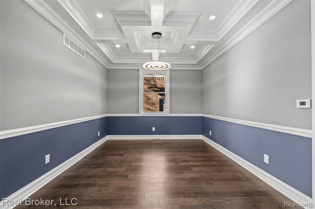Spare room with dark wood-type flooring, coffered ceiling, beam ceiling, recessed lighting, and crown molding
