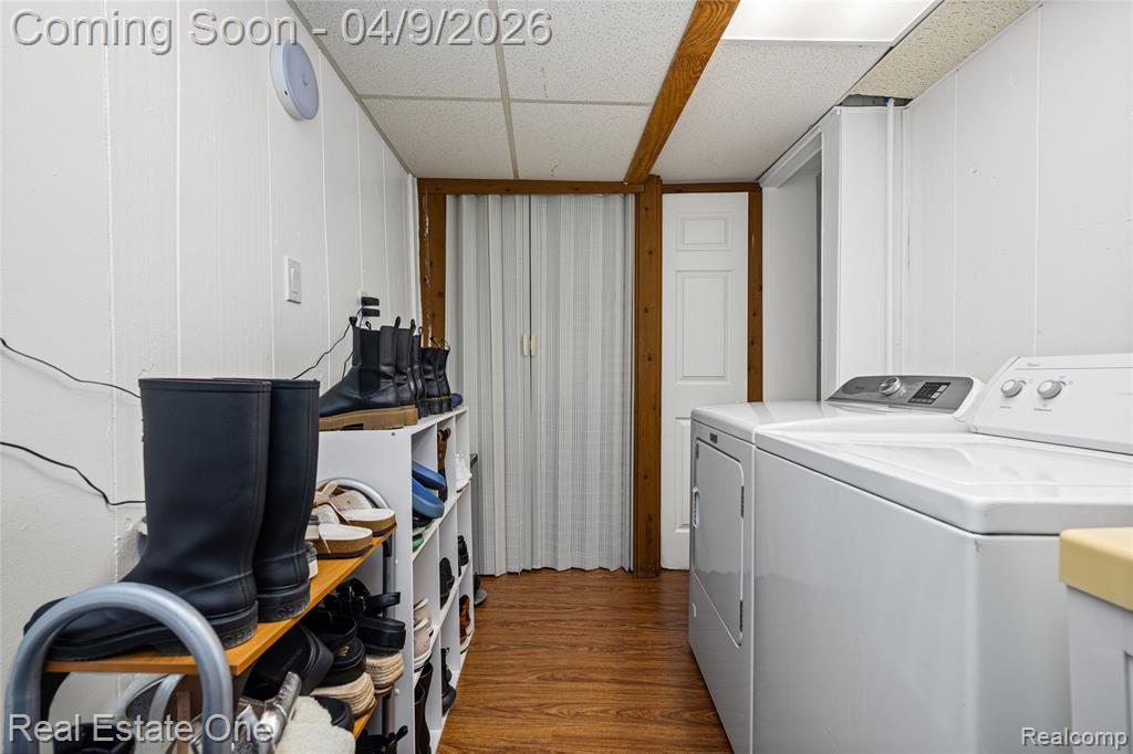 Laundry area with dark wood-type flooring, a drop ceiling, and washing machine and clothes dryer