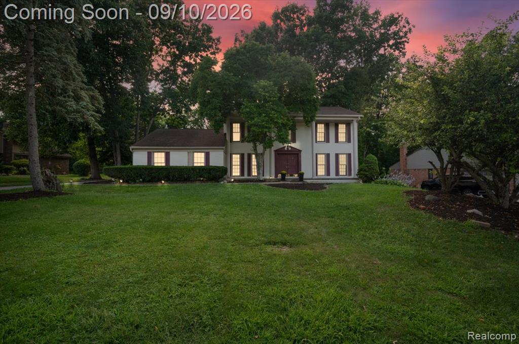 Two-story residence featuring a classic facade, mature trees, and landscaping