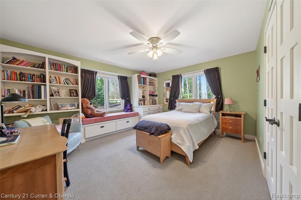 Bedroom featuring light colored carpet, multiple windows, a closet, and a ceiling fan