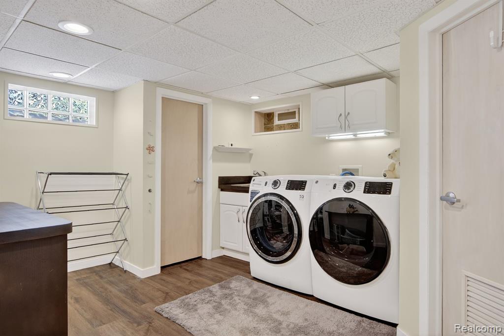 Laundry room featuring cabinet space, separate washer and dryer, dark wood-type flooring, and a paneled ceiling