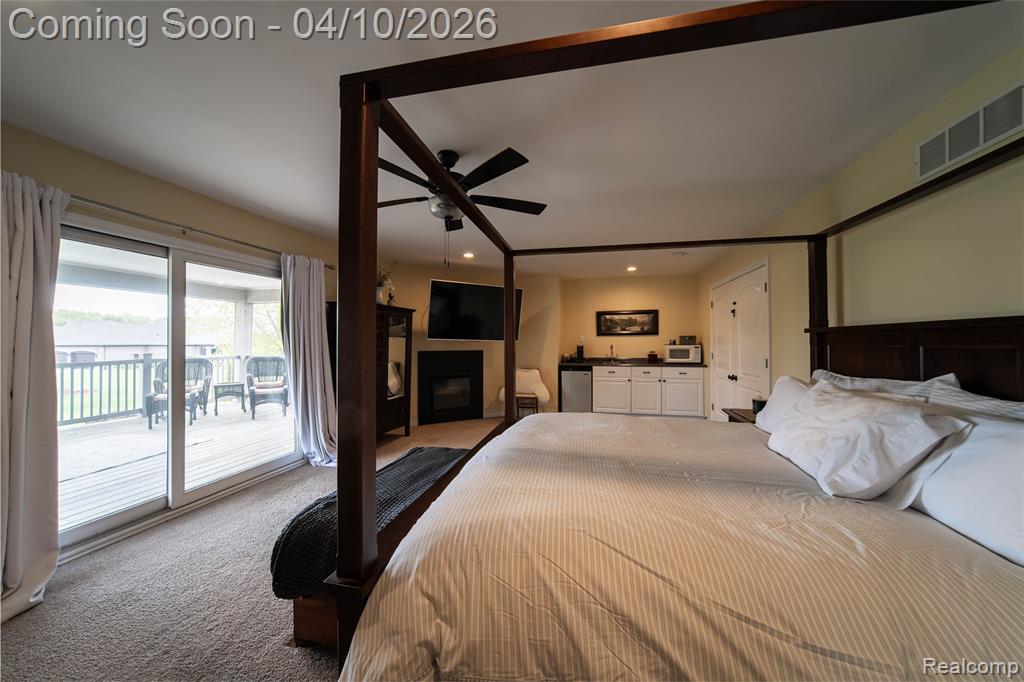 Carpeted bedroom featuring access to exterior, a fireplace, ceiling fan, and recessed lighting
