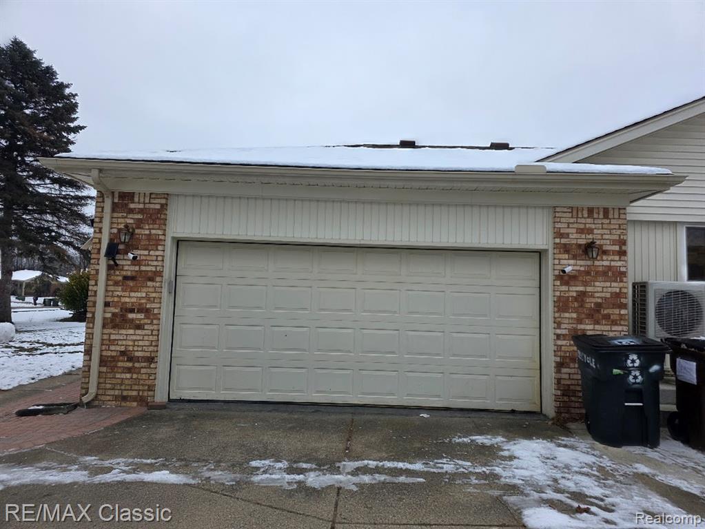Snow covered garage featuring driveway