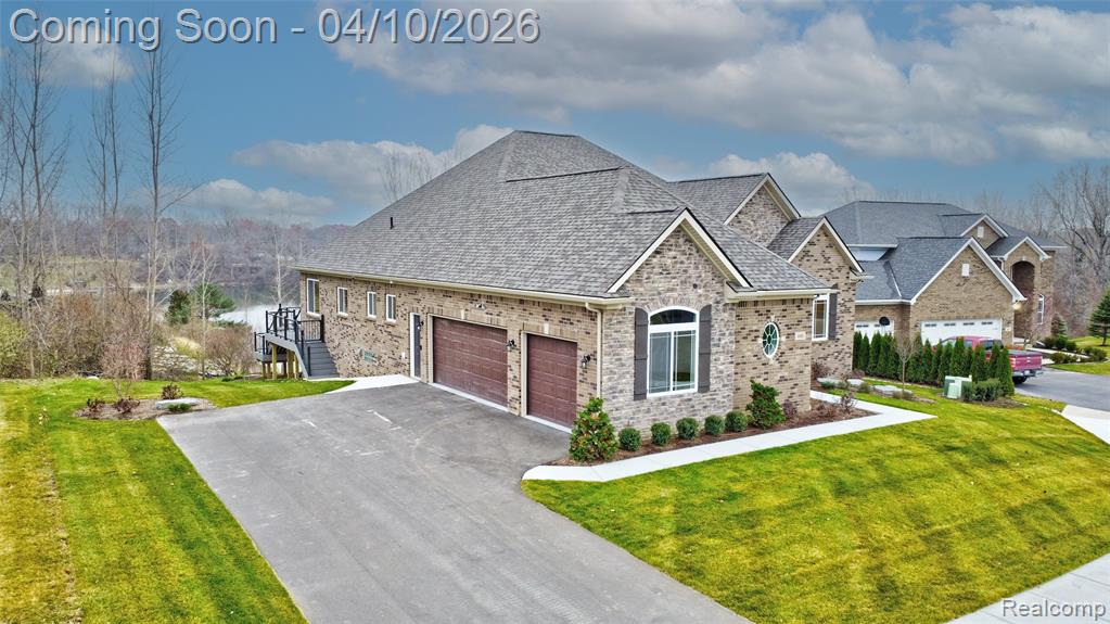 View of front of home with a front yard, asphalt driveway, a garage, brick siding, and a shingled roof