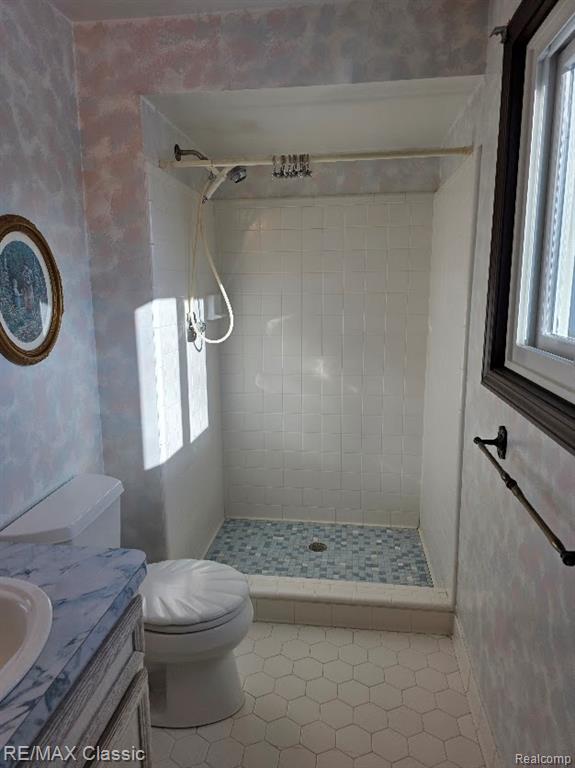 Bathroom with healthy amount of natural light, a shower stall, and vanity