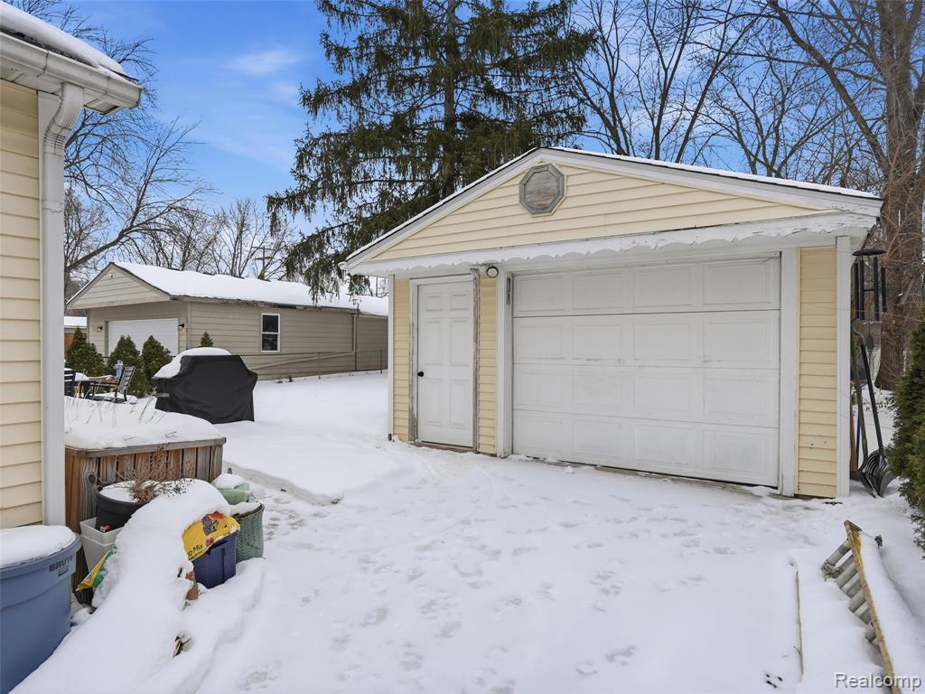 Snow covered garage featuring a detached garage