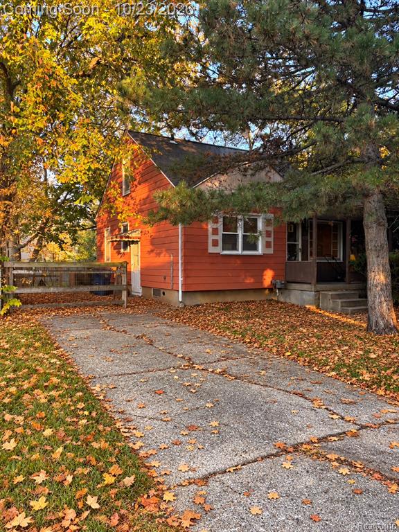 Exterior featuring horizontal siding, concrete driveway, covered porch with concrete steps, and wood-panel fencing
