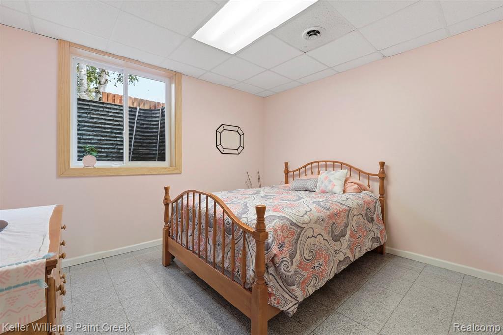 Recessed window with wood trim, drop ceiling with integrated lighting, and tile flooring