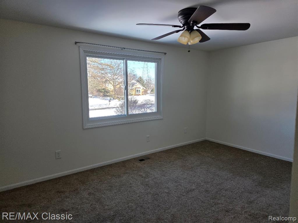 Spare room featuring carpet and ceiling fan