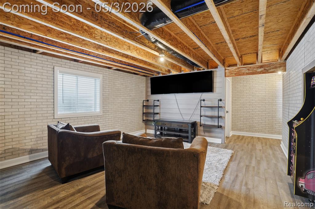 Alternative view area featuring brick wall and wood finished floors
