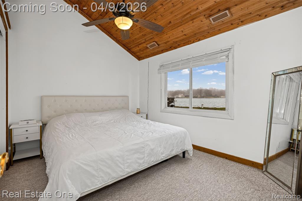 Bedroom featuring light carpet, a vaulted wooden ceiling, and ceiling fan