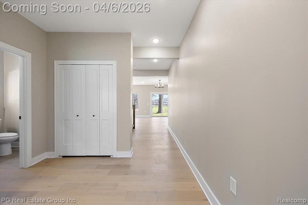 Hall featuring light wood-style flooring and suspended lighting