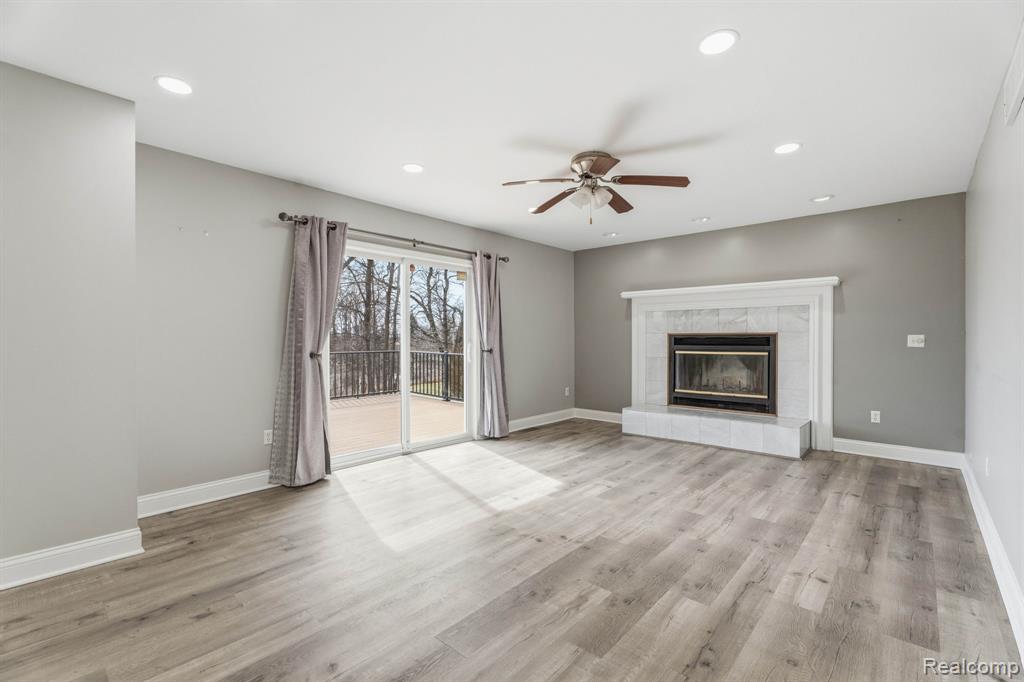 Unfurnished living room featuring ceiling fan, a tile fireplace, light wood finished floors, and recessed lighting