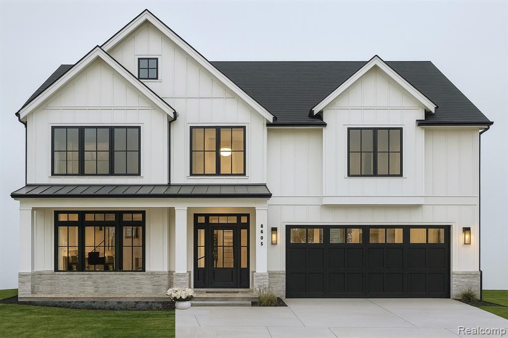 Modern inspired farmhouse featuring board and batten siding, a standing seam roof, and an attached garage