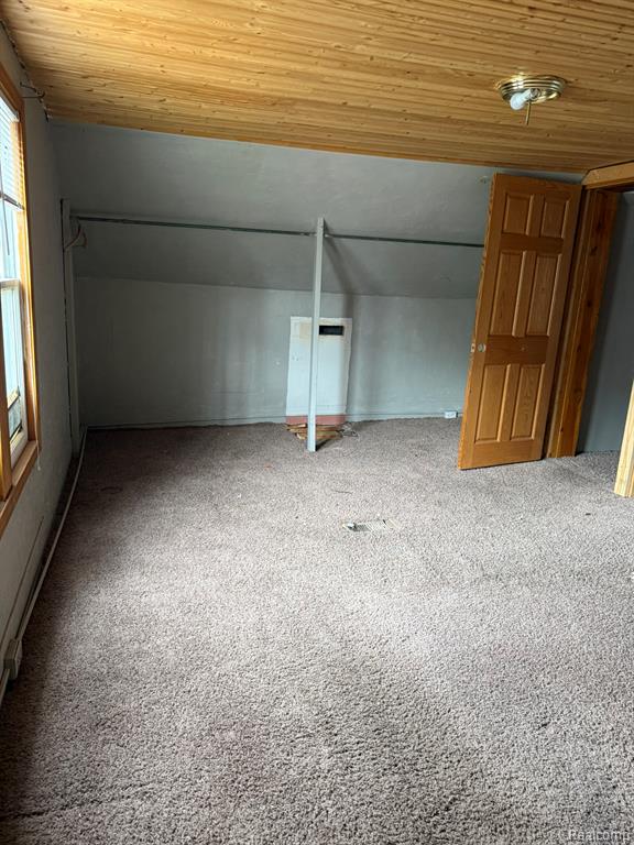 Additional living space featuring carpet flooring and a vaulted wood ceiling